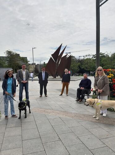 Group of people standing on square two with service dogs
