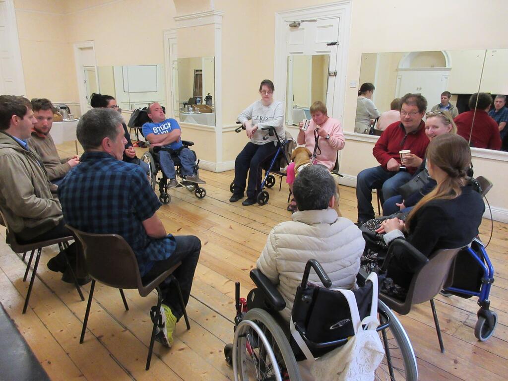 A group of people with disabilities sitting in a circle having a discussion